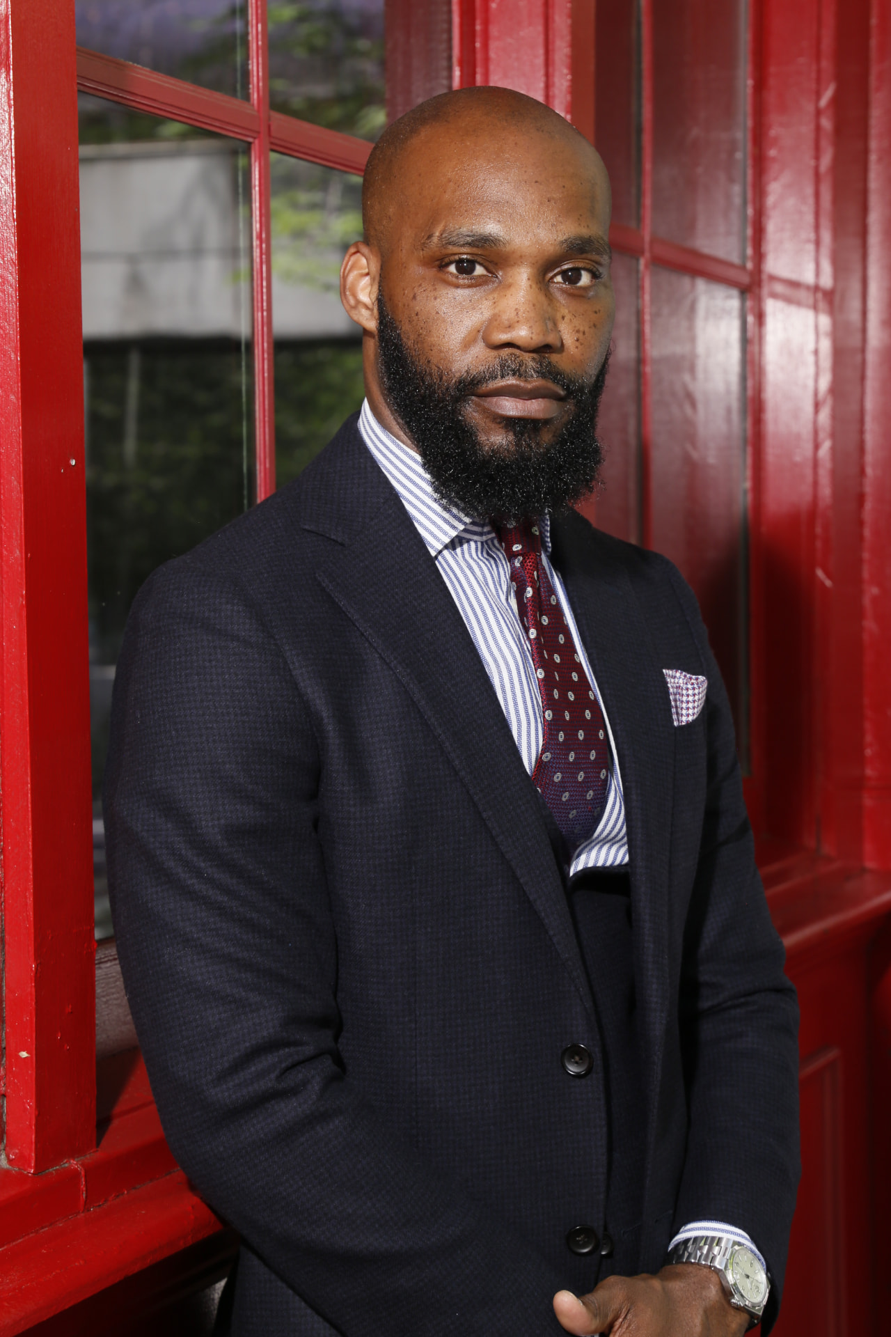 Adrian Provost, CEO of ONE Terminus, in a navy suit in front of red-framed windows